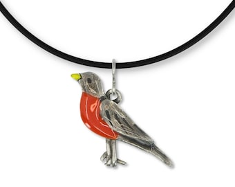May include: A silver necklace with a red and gray robin pendant. The robin has a yellow beak and is perched on a branch.