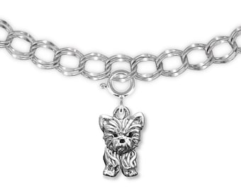 May include: A silver-toned charm bracelet featuring a detailed Yorkshire Terrier dog charm. The charm is suspended from a silver chain with a lobster clasp. The dog charm is intricately designed, showcasing the breed's distinctive features.