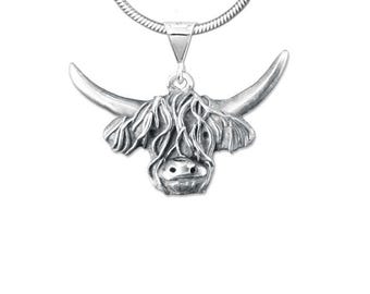 May include: A silver-colored pendant necklace featuring a Highland cow head. The pendant has detailed features including horns, shaggy fur, and a nose. The necklace chain is a silver-colored snake chain. The pendant is suspended from a triangular bail.