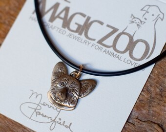 May include: A black choker necklace with a bronze pendant featuring a detailed portrait of a Pembroke Welsh Corgi. The necklace is on a white card with the text "The Magic Zoo Handcrafted Jewellery for Animal Lovers".