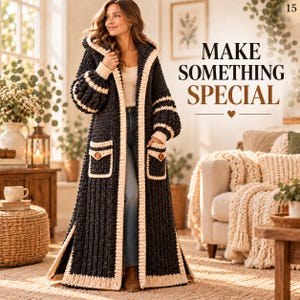May include: A long, dark charcoal grey crochet hooded cardigan featuring cream-coloured trim along the edges, cuffs, and two front pockets. The garment includes brown buttons on the pockets and the text "MAKE SOMETHING SPECIAL" printed in the upper right corner.