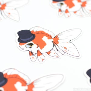 Puede incluir: Una pegatina de un pez dorado de dibujos animados con un sombrero de copa y un mon&oacute;culo. El pez dorado es naranja y blanco con un sombrero de copa negro y un mon&oacute;culo dorado.