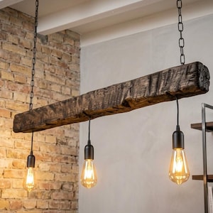 May include: A rustic pendant light fixture featuring a long, dark, weathered wooden beam suspended by two black metal chains. Three black sockets hang from the beam, each fitted with a clear, glowing Edison-style light bulb emitting warm light.