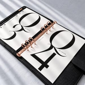 May include: A black leather six-ring binder with rose gold metal rings, containing white paper inserts. The left page features the large black text 3 QUARTER and the right page features the large black text 4 QUARTER, both labeled ELAYAE PAPER.