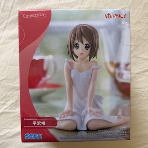 Pode incluir: Uma caixa de figura de anime Sega Yumemirize com um personagem de cabelo castanho curto vestindo um vestido branco. A embalagem inclui o texto Yumemirize, K-On! e os caracteres japoneses para Yui Hirasawa. O design tem detalhes vermelhos.
