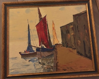 Puede incluir: Una pintura al óleo en un marco dorado y negro que muestra veleros amarrados a lo largo de un muelle de piedra. La escena presenta una vela roja, una azul y una amarilla bajo un cielo pálido. El muelle está bordeado por edificios oscuros.