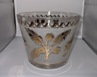 May include: A clear glass bowl featuring a frosted band around the center, decorated with gold floral motifs and leaves. The upper rim is adorned with a gold zigzag pattern, and a thin gold line encircles the base of the glass vessel.