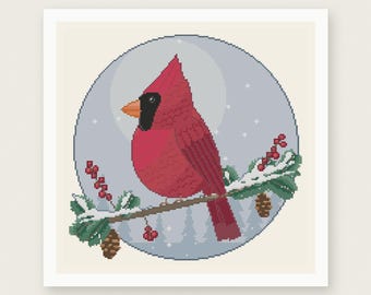Può includere: Uno schema a punto croce raffigurante un cardinale rosso appollaiato su un ramo di pino innevato con bacche rosse e pigne, su uno sfondo circolare azzurro con stelle bianche e il testo PDF PATTERN INSTANT DOWNLOAD.