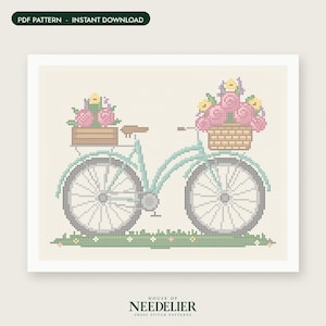 May include: A cross stitch pattern featuring a light blue bicycle with a brown wooden crate on the back and a woven basket on the front, both filled with pink and yellow flowers. The bicycle sits on a green grassy patch with small flowers.