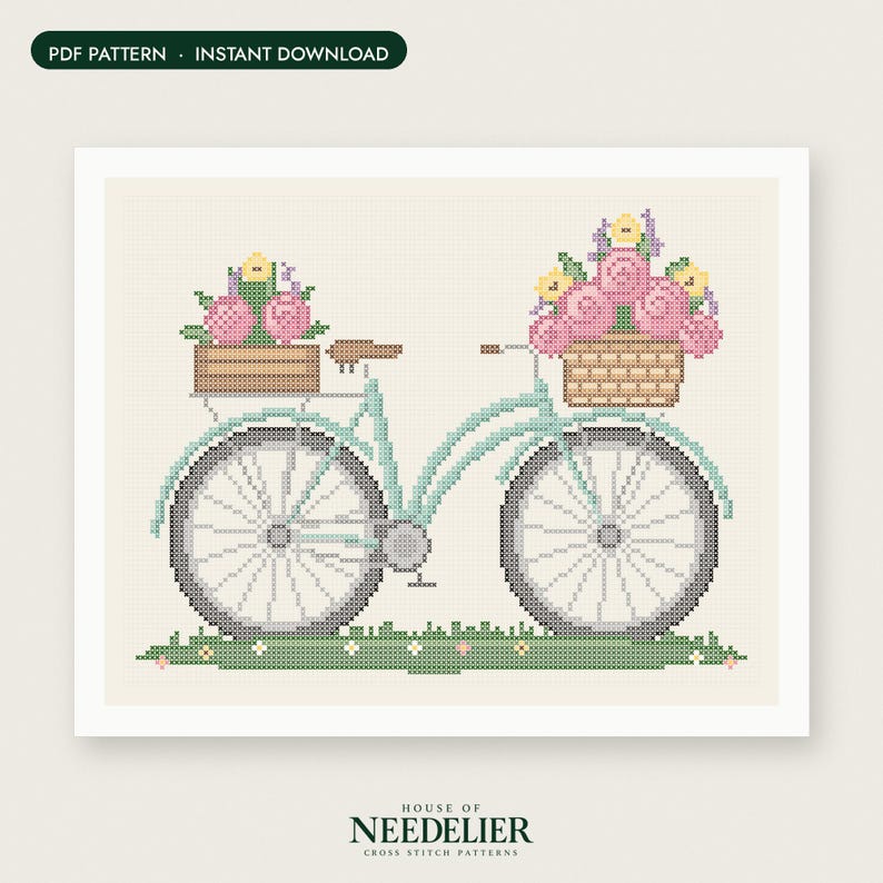 May include: A cross stitch pattern featuring a light blue bicycle with a brown wooden crate on the back and a woven basket on the front, both filled with pink and yellow flowers. The bicycle sits on a green grassy patch with small flowers.