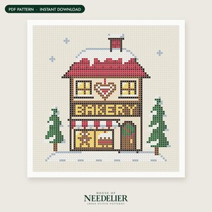 May include: A cross stitch pattern featuring a two-story bakery building with a red roof covered in snow, a heart design, and the word BAKERY in yellow letters. The scene includes two green pine trees and light blue snowflakes on a beige background.