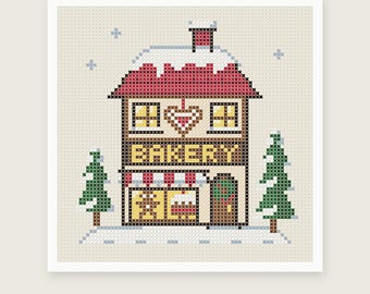 May include: A cross stitch pattern featuring a two-story bakery building with a red roof covered in snow, a heart design, and the word BAKERY in yellow letters. The scene includes two green pine trees and light blue snowflakes on a beige background.