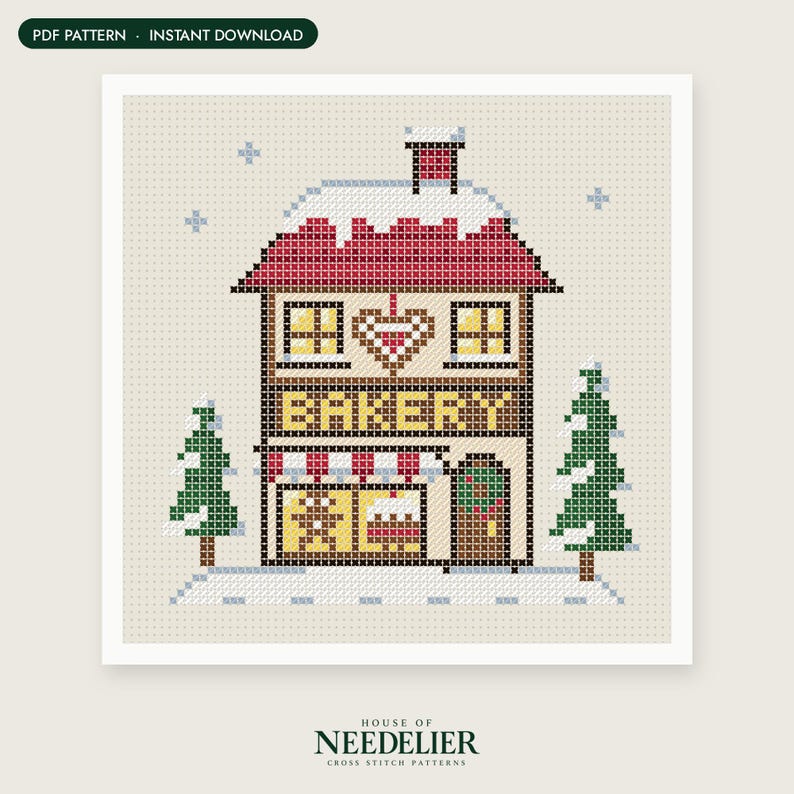 May include: A cross stitch pattern featuring a two-story bakery building with a red roof covered in snow, a heart design, and the word BAKERY in yellow letters. The scene includes two green pine trees and light blue snowflakes on a beige background.