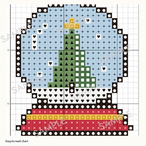 May include: A cross-stitch pattern chart featuring a snow globe design. The globe contains a green Christmas tree on a light blue background with black plus signs and heart symbols. The base is red with a yellow stripe and black symbols.