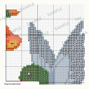 May include: A cross-stitch pattern chart on a white grid background featuring a stylized bird design. The pattern uses various symbols like squares, triangles, and hearts to represent colors including orange, light blue, and dark green. Text reads Easy-to-read chart.