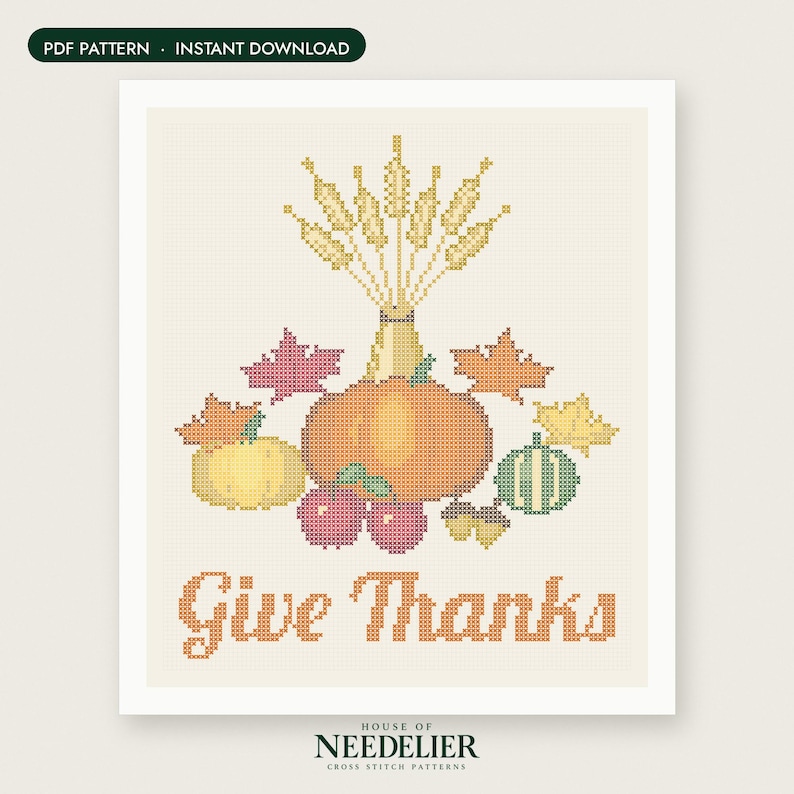 May include: A cross stitch pattern featuring a central orange pumpkin, a yellow pumpkin, a green striped gourd, red apples, acorns, and autumn leaves. Above the produce is a bundle of wheat stalks. The text "Give Thanks" is in orange below.