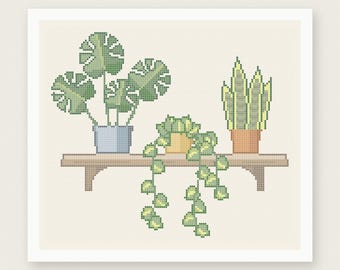 May include: A cross stitch pattern featuring three potted plants on a wooden shelf. The plants include a monstera in a blue pot, a trailing plant in a yellow pot, and a snake plant in a terracotta pot. Text reads PDF PATTERN INSTANT DOWNLOAD.