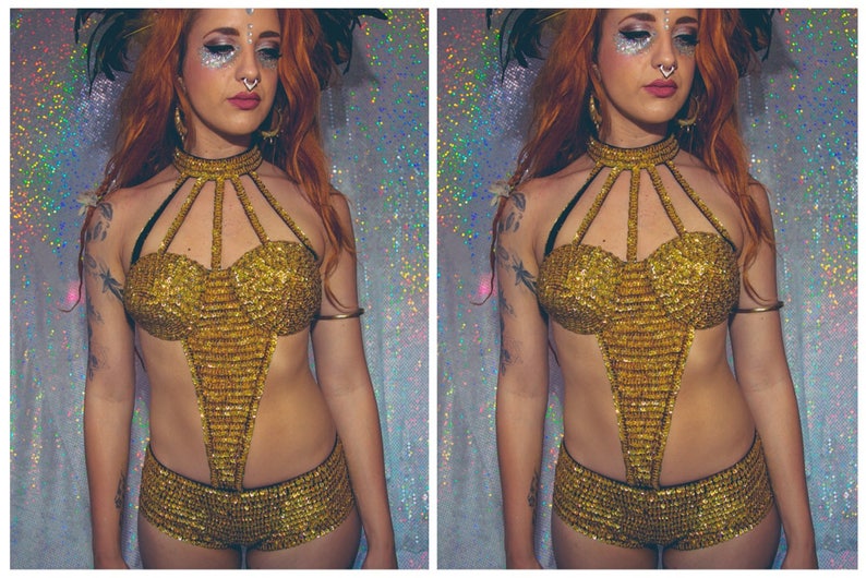 K&ouml;nnte beinhalten: Ein goldenes, paillettenbesetztes zweiteiliges Outfit mit einem Halstuch und Shorts. Das Outfit hat ein geometrisches Design und wird von einer Person mit roten Haaren und Make-up getragen.