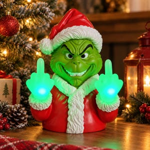 May include: A green character figurine wearing a red Santa suit with white fur trim and a matching hat. The figure has a mischievous facial expression and holds up both hands with glowing green middle fingers extended in a gesture.