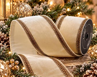 May include: A roll of cream-colored velvet ribbon featuring metallic gold braided trim along both edges. The ribbon is wound on a black spool with white text and is displayed with a smooth, soft texture and a consistent, elegant finish.