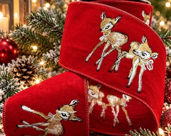 May include: A wide red velvet ribbon featuring an embroidered pattern of light brown fawns with white accents. The ribbon has a wired edge and displays multiple deer figures in various poses across the deep red fabric surface.
