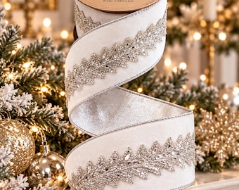 May include: A spool of white velvet ribbon featuring a silver metallic underside and a decorative border of clear crystal rhinestones arranged in a leaf-like pattern. The top of the spool is labeled with the text d.stevens fine ribbons.
