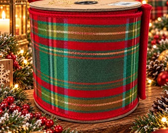 May include: A wide spool of fabric ribbon featuring a classic plaid pattern in shades of red, dark green, and gold. The ribbon has a finished edge and is wrapped around a circular cardboard core, displaying a consistent woven texture throughout.