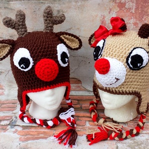 May include: Two crocheted reindeer hats with brown and beige yarn. One hat has a red nose and the other has a white nose. Both hats have black eyes and a red and white braided cord.