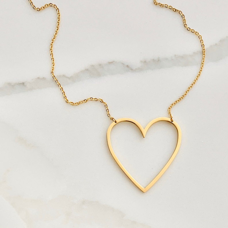 Op de afbeelding: Een gouden ketting met een grote, open hart hanger.