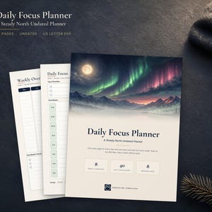May include: A Daily Focus Planner with a cover featuring a moonlit aurora borealis over mountains. The planner includes pages for weekly overviews and daily focus tasks. Text on the cover reads Daily Focus Planner, A Steady North Undated Planner, 8 weekly overviews, 40 daily focus pages, and 8 weekend pages.