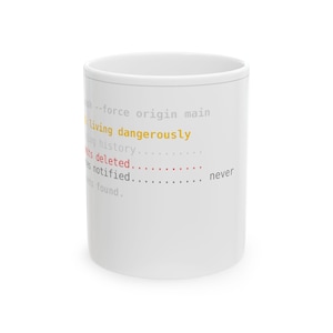 May include: A white ceramic mug featuring printed text in various colors. The text reads: push --force origin main, living dangerously, long history, commits deleted, files notified, never, and commits found.