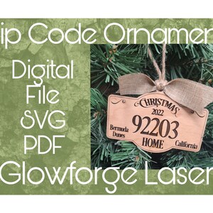 Op de afbeelding: Een houten kerstversiering met de tekst "Christmas 2022" en de postcode "92203". De versiering heeft ook de tekst "Bermuda Dunes" en "California". De versiering hangt aan een kerstboom.