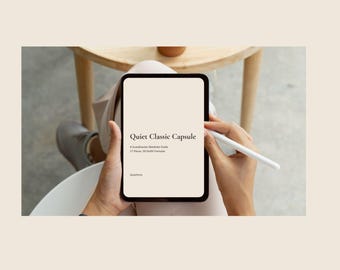 May include: A black tablet displaying the text Quiet Classic Capsule, A Scandinavian Wardrobe Guide, 17 Pieces, 30 Outfit Formulas, and Quietform. A white stylus is held against the screen of the tablet, which has a light beige background.
