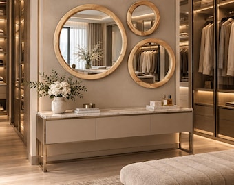 May include: A long console table with a marble top and light beige drawers, supported by a thin metal frame. Above it, three round mirrors with light wood frames are mounted on the wall. A white vase with flowers sits on the table.