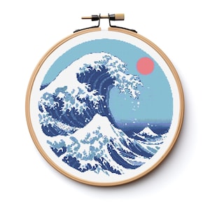 May include: A cross-stitch embroidery of the Great Wave off Kanagawa, a famous Japanese woodblock print by Hokusai. The wave is depicted in shades of blue, with a red sun in the background.
