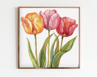May include: A framed cross-stitch embroidery featuring three tulips in shades of pink, orange, and yellow. The tulips are arranged in a bouquet with green leaves.