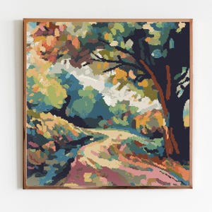 May include: A framed cross-stitch artwork depicting a winding path through a colorful forest. The path is lined with trees and foliage in shades of green, blue, yellow, and orange.