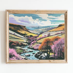 May include: A framed painting depicting a valley landscape with a river winding through it. The valley is surrounded by hills and trees, and the sky is a bright blue with white clouds. The painting is in a rustic wooden frame.
