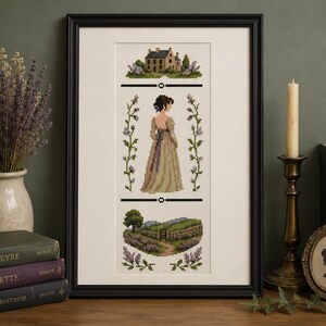 May include: A framed cross-stitch embroidery featuring a central figure in a long tan dress, a stone house at the top, and a rural landscape at the bottom. The design is bordered by vertical floral sprigs and two horizontal black lines.