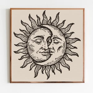 Puede incluir: Una impresión enmarcada con una ilustración en blanco y negro del sol y la luna. El sol tiene una cara con los ojos cerrados, y la luna está dentro. La obra de arte está sobre un fondo beige.