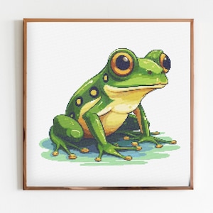 Könnte beinhalten: Ein grüner Frosch mit gelben Flecken und großen schwarzen Augen sitzt auf einer hellgrünen Oberfläche. Der Frosch blickt nach rechts.