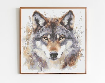 May include: A framed cross-stitch artwork featuring a detailed portrait of a wolf. The wolf has gray, brown, and white fur, with amber eyes and a black nose. The artwork is set against a white background, with a brown frame.