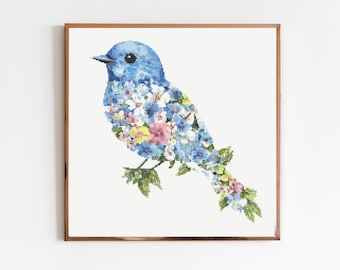 May include: A framed print featuring a blue bird design. The bird's body is filled with a floral pattern in shades of blue, pink, and yellow. The artwork is set against a white background.