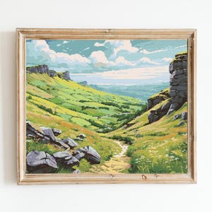 May include: A framed painting depicting a green valley with a winding path leading to a rocky cliff. The sky is blue with white clouds and the valley is filled with lush green grass and trees.
