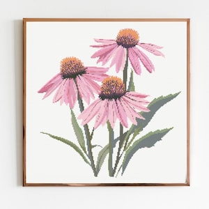 May include: A framed print featuring a cross-stitch design of three pink coneflowers. The flowers have orange centers and green leaves, set against a white background. The frame is a warm brown color.