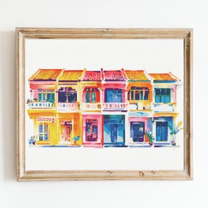 Könnte beinhalten: Eine farbenfrohe Illustration einer Reihe von vier Häusern mit roten Ziegeldächern, gelben, rosa und blauen Wänden und weißen Verzierungen. Die Häuser haben weiße Balkone und Fenster mit bunten Fensterläden.