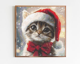 May include: A cute kitten wearing a red Santa hat with a white pom-pom and a red bow tie. The kitten is looking up with big, curious eyes. The background is a snowy winter scene.