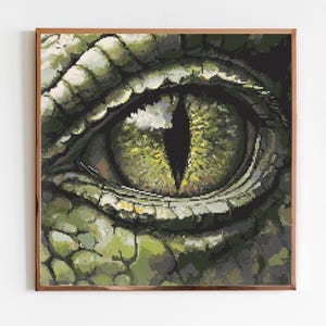 Peut inclure: Impression encadrée représentant un gros plan sur un œil de reptile. L'œil a une pupille noire et verticale et est entouré d'écailles vertes et jaunes. L'œuvre est détaillée et réaliste, avec un accent sur la texture et la lumière.