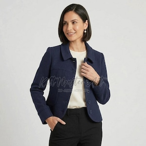 Può includere: Una giacca blu navy in misto lana con colletto strutturato, maniche lunghe e chiusura frontale con bottoni. La giacca è indossata sopra un top color crema e abbinata a pantaloni neri. Una filigrana riporta la scritta Kilt Master Accessories.