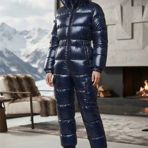 Puede incluir: Un mono acolchado de color azul marino con acabado brillante, cuello alto, cremallera frontal completa, cintura entallada y mangas largas con puños elásticos. El pantalón incluye bolsillos laterales tipo cargo y tobillos elásticos, combinado con botas negras.